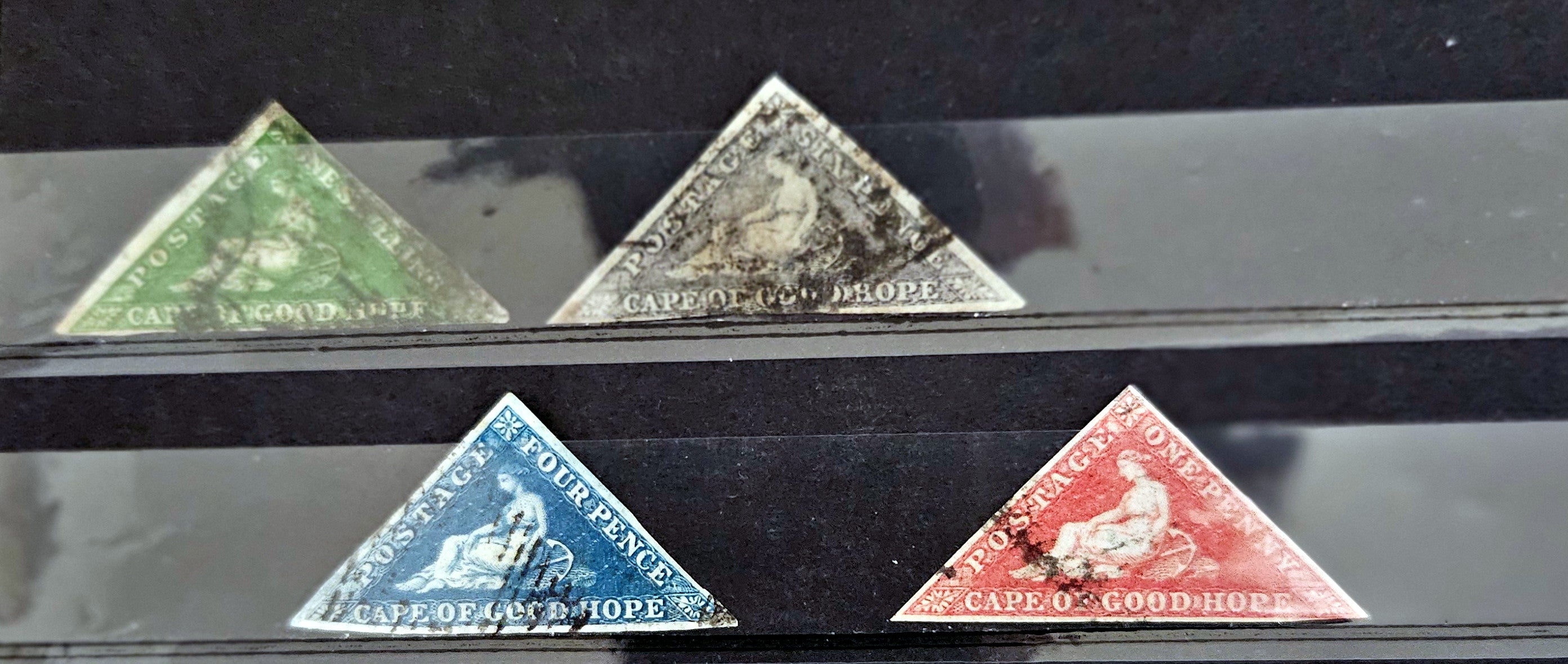 Four triangular stamps from Cape of Good Hope on a black background