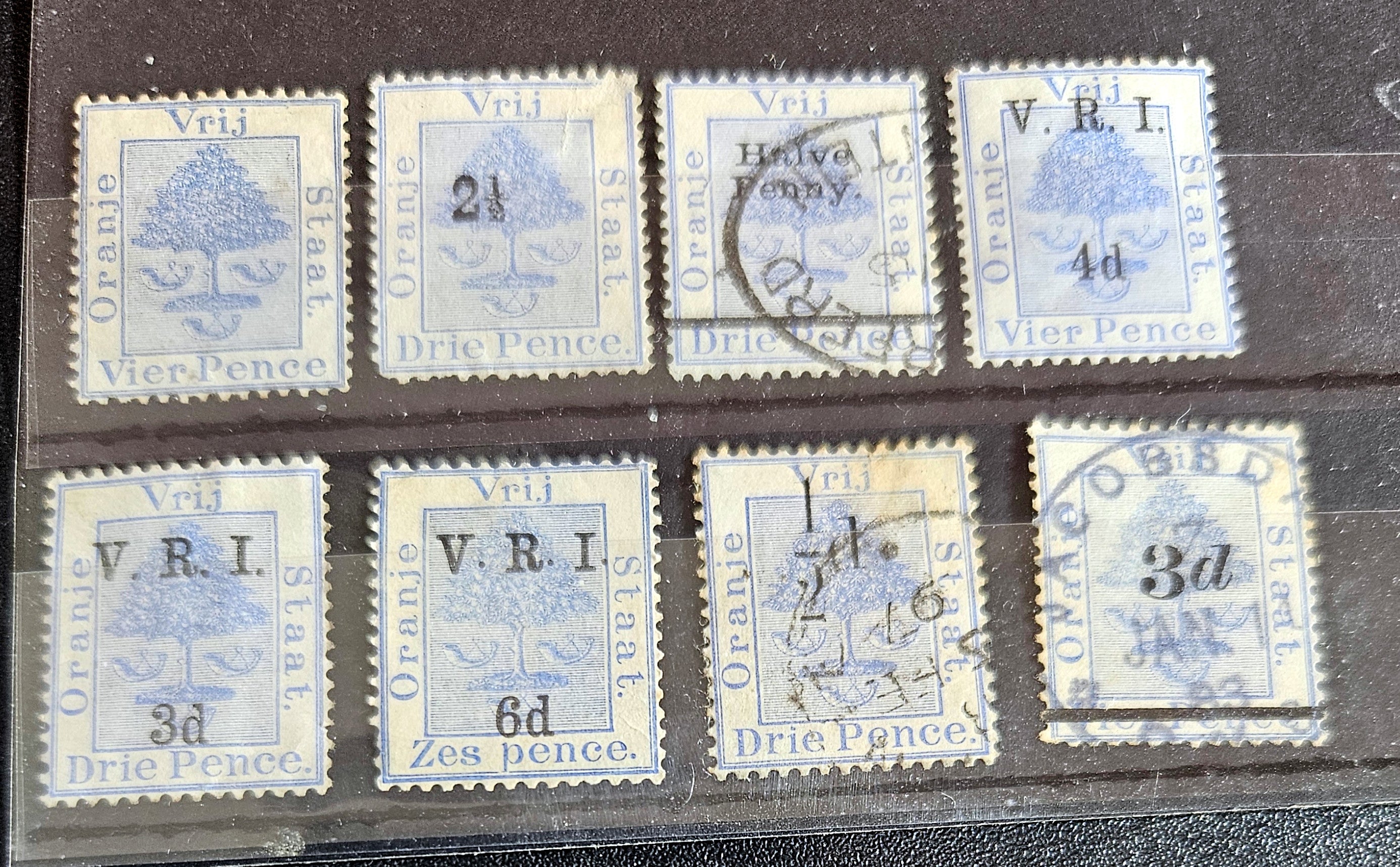 A collection of vintage postage stamps from the Orange Free State, featuring various denominations and cancellation marks, housed in a plastic sleeve.