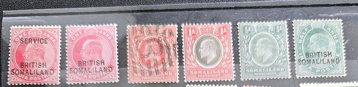 Six vintage British Somaliland postage stamps displayed side by side in a black case. The stamps show different denominations and colors including pink, red, orange, green, and blue, with some cancellation marks.