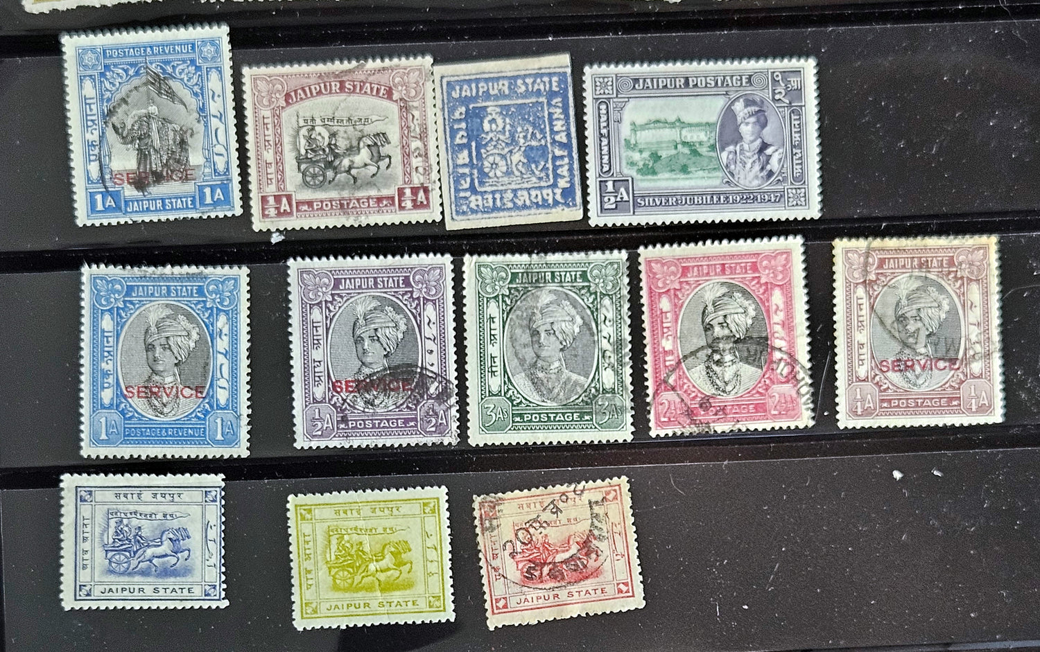 A collection of vintage stamps from Jaipur, India, featuring various designs and denominations, with visible signs of wear.