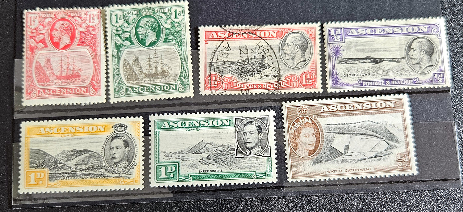 A collection of British Commonwealth Ascension vintage stamps displayed on a surface, featuring various colors and images representing different historical periods.
