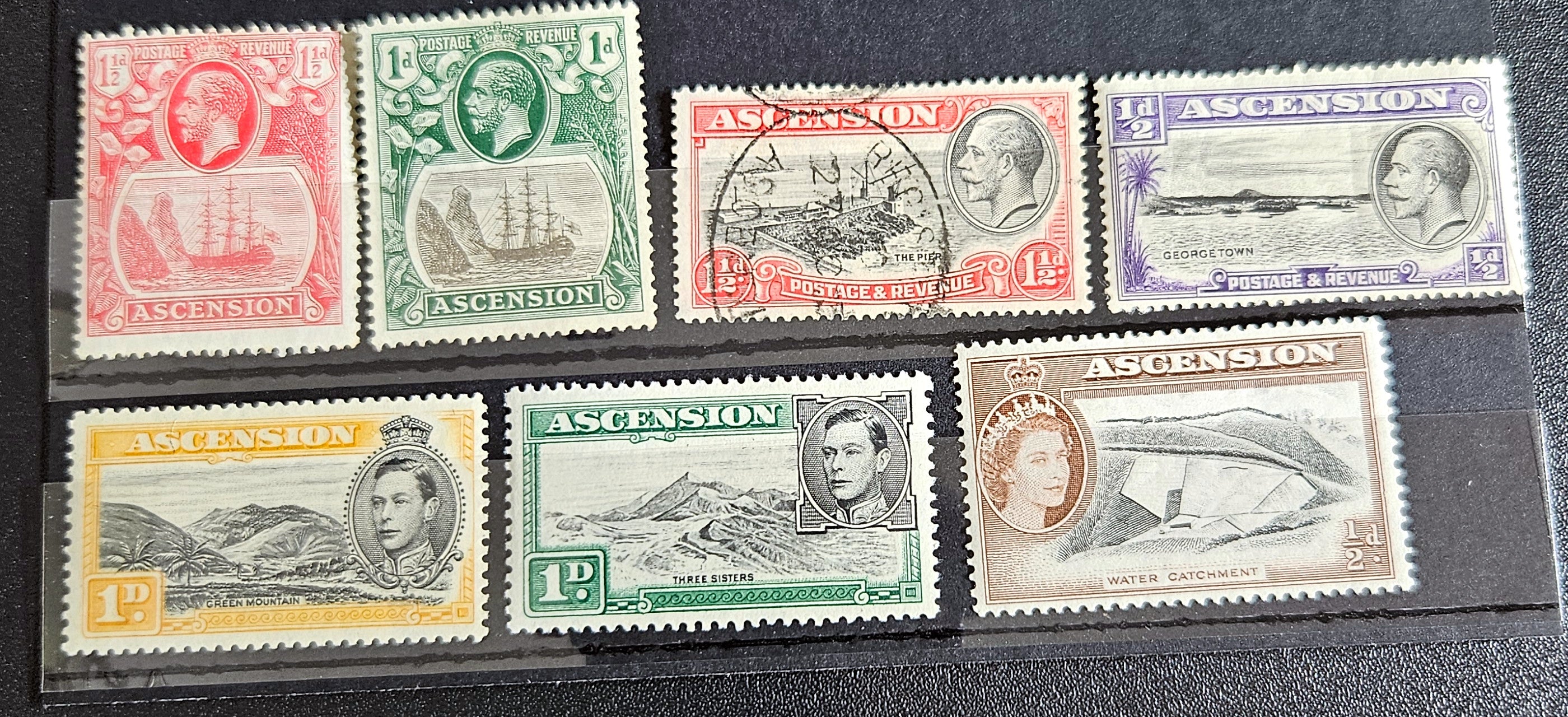 A collection of British Commonwealth Ascension vintage stamps displayed on a surface, featuring various colors and images representing different historical periods.