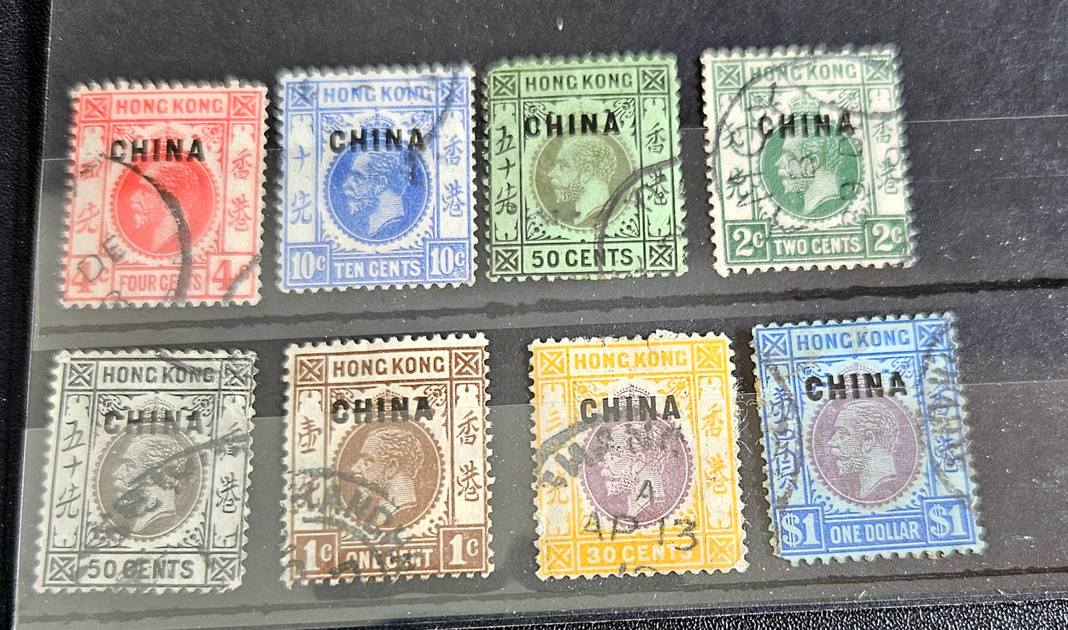 A collection of vintage Hong Kong stamps from various queens to post-handover issues, displayed on a surface.