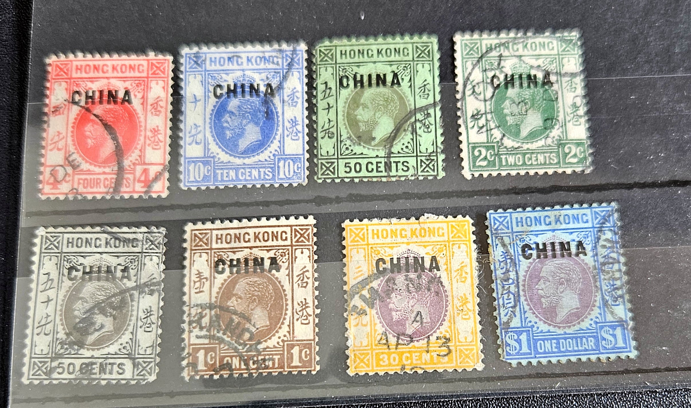 A collection of vintage Hong Kong stamps from various queens to post-handover issues, displayed on a surface.