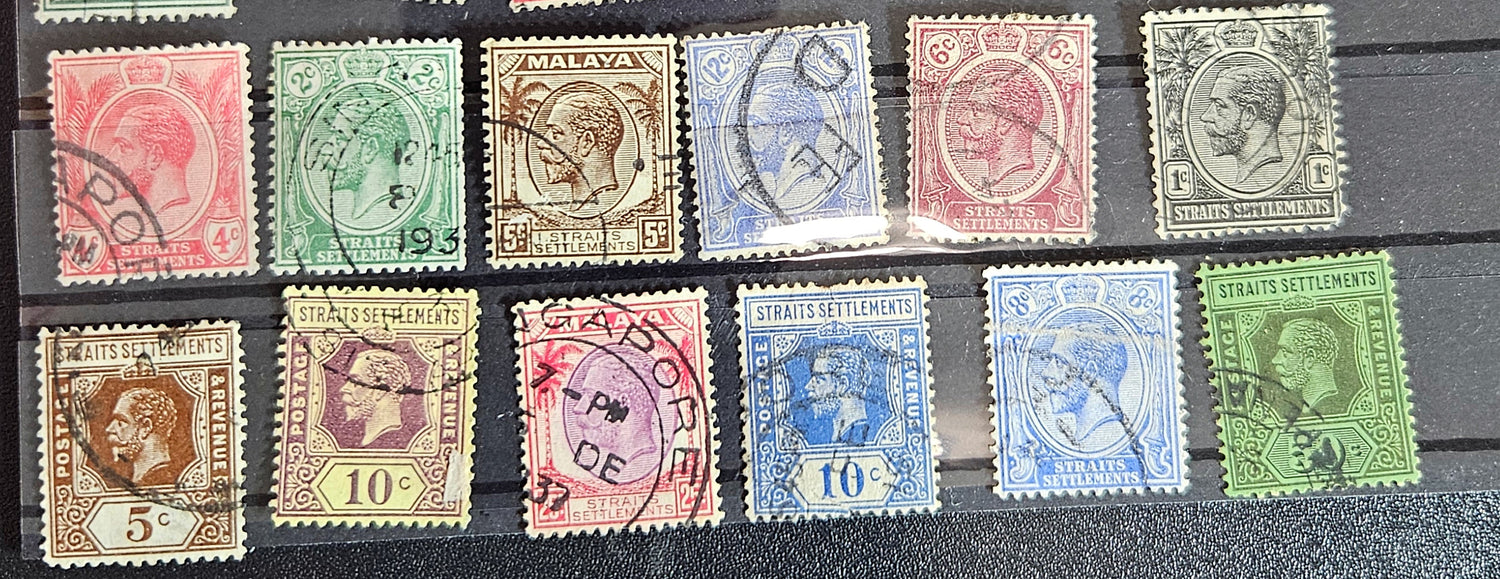 A collection of vintage postage stamps from the Straits Settlements, featuring various colors and designs, displayed on a flat surface.