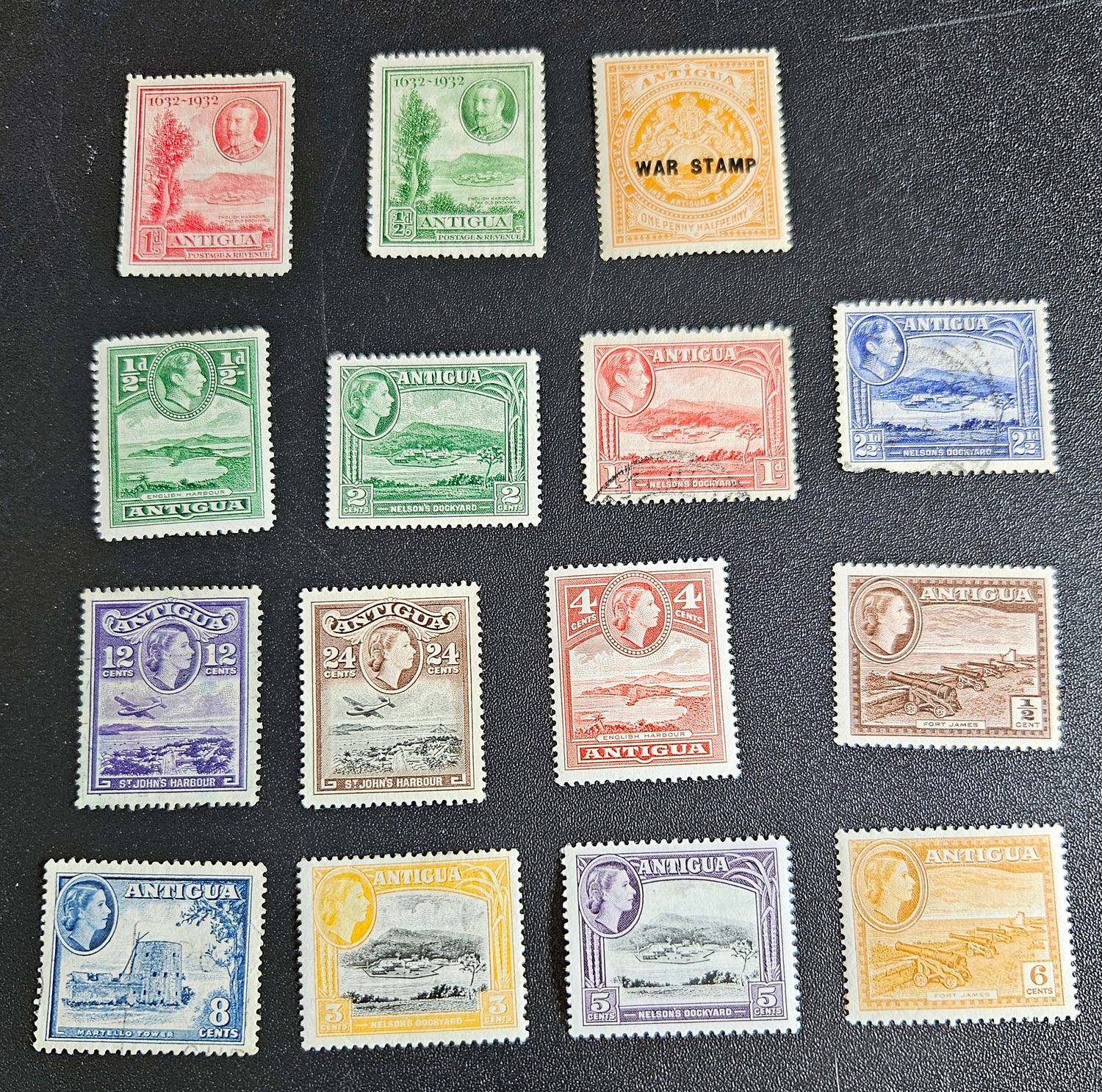 A collection of vintage Antigua postage stamps from the British Commonwealth, featuring various colors and designs, some depicting Queen Elizabeth II and others with scenic views.