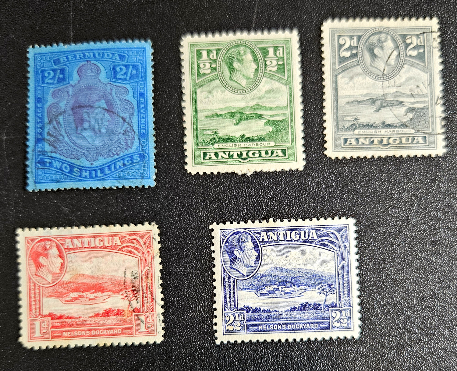 A collection of vintage Antigua postage stamps from the British Commonwealth, featuring various colors and designs, some depicting Queen Elizabeth II and others with scenic views.
