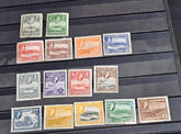 A collection of vintage Antigua postage stamps from the British Commonwealth, featuring various colors and designs, some depicting Queen Elizabeth II and others with scenic views.
