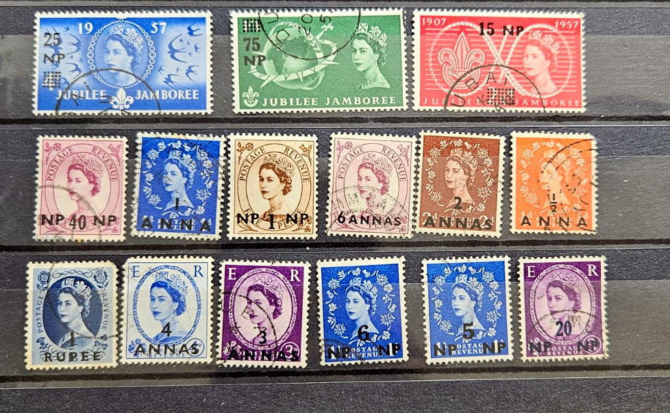 A set of twelve vintage Queen Elizabeth II British colony postage stamps from 1957, arranged in three rows on a stack