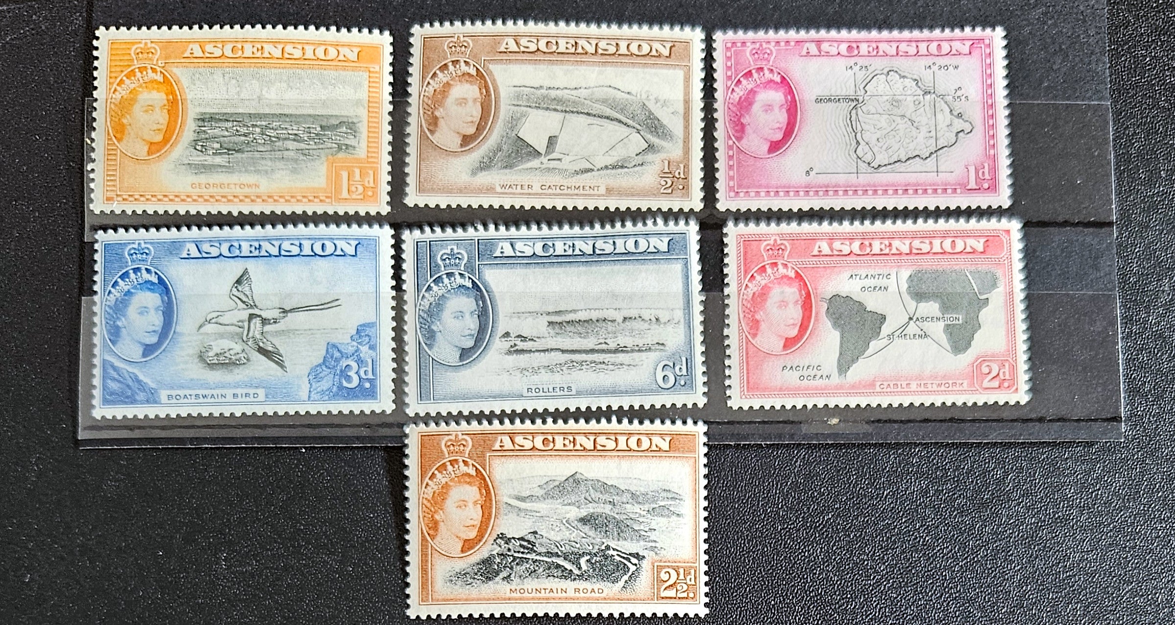 A collection of British Commonwealth Ascension vintage stamps displayed on a surface, featuring various colors and images representing different historical periods.