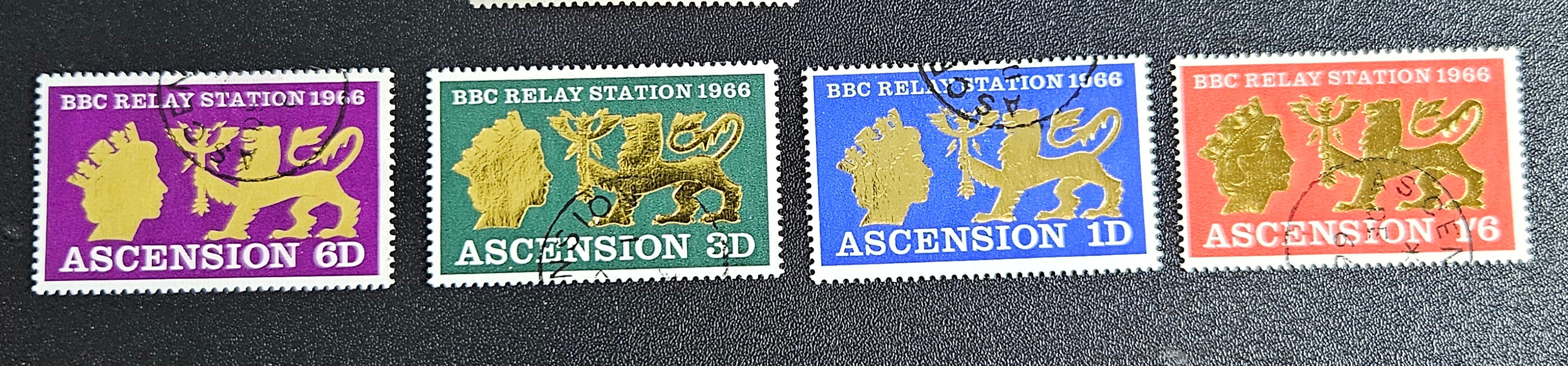 A collection of British Commonwealth Ascension vintage stamps displayed on a surface, featuring various colors and images representing different historical periods.