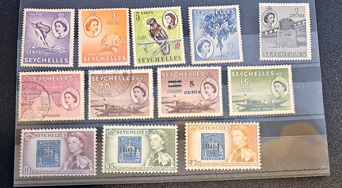 A set of vintage Seychelles postage stamps displayed inside a clear plastic protective sleeve, arranged in three rows on a dark textured surface.