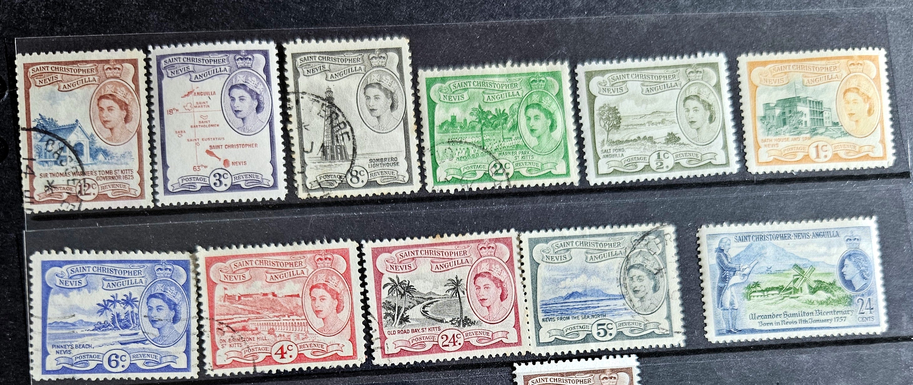 A collection of vintage St Kitts and Nevis stamps displayed against a dark background. The stamps vary in color and design, featuring various denominations and historical figures.