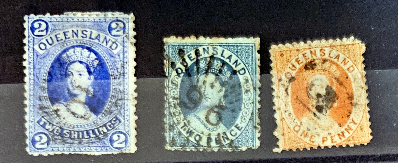 Three vintage postage stamps from Queensland on a dark background