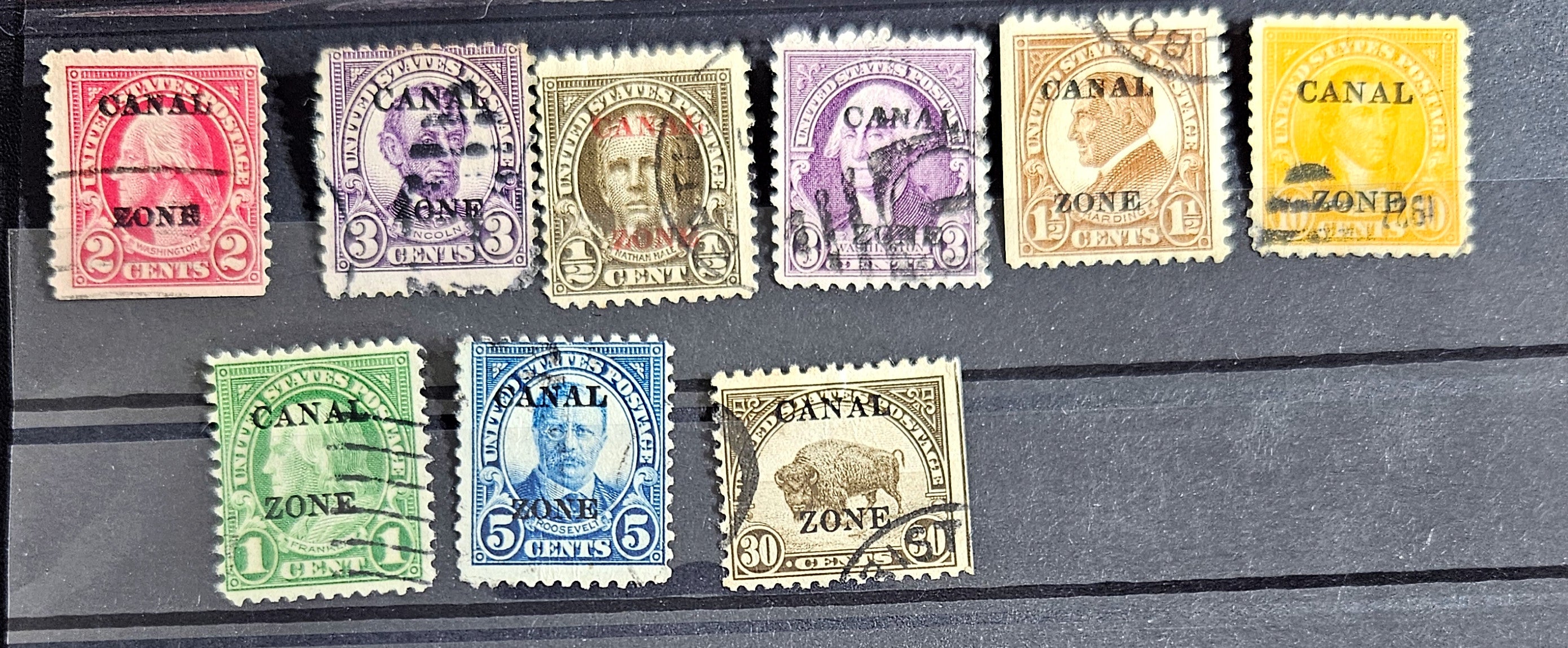 A collection of vintage postage stamps from the Panama Canal Zone, featuring various colors and designs, some with over-printed text.