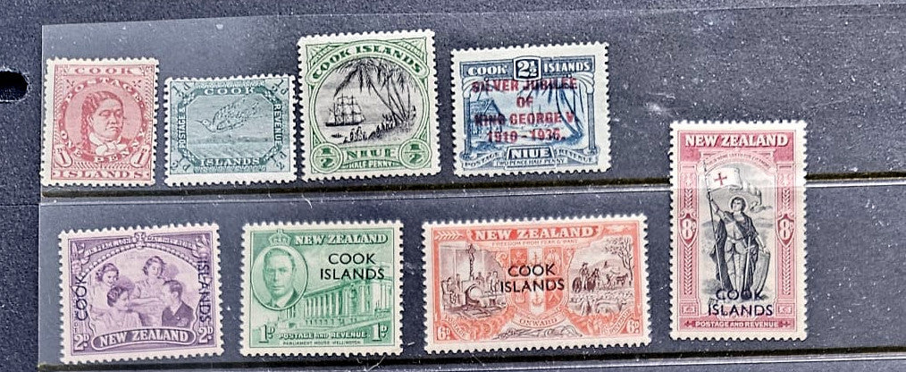 A set of vintage Cook Islands and New Zealand postage stamps displayed on a dark textured background, featuring multiple colors including green, blue, pink, purple, and orange.