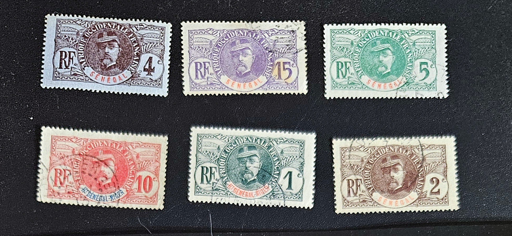 A set of eight vintage stamps from French Senegal with various designs and denominations displayed against a black background.