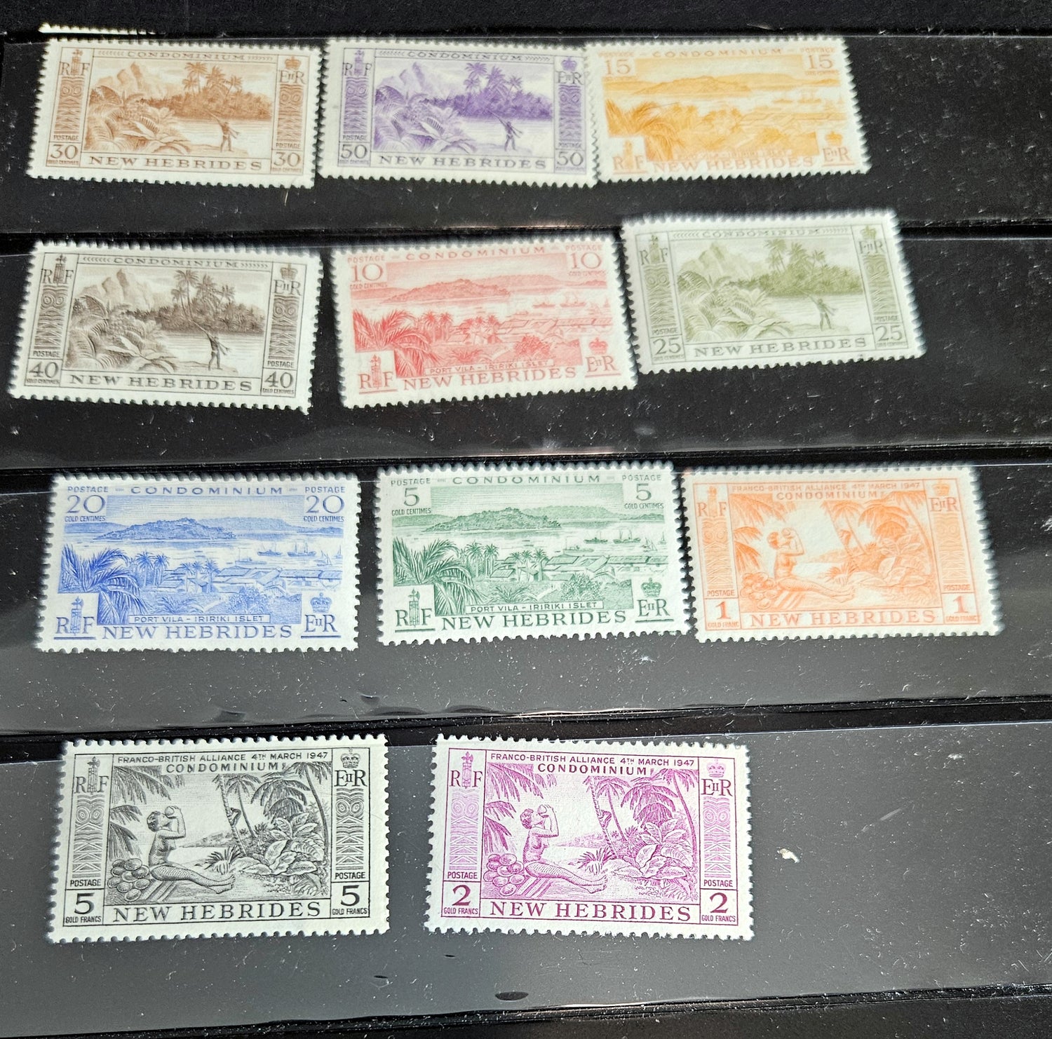 A collection of postage stamps from the New Hebrides, featuring various images and colors, arranged in rows on a surface.