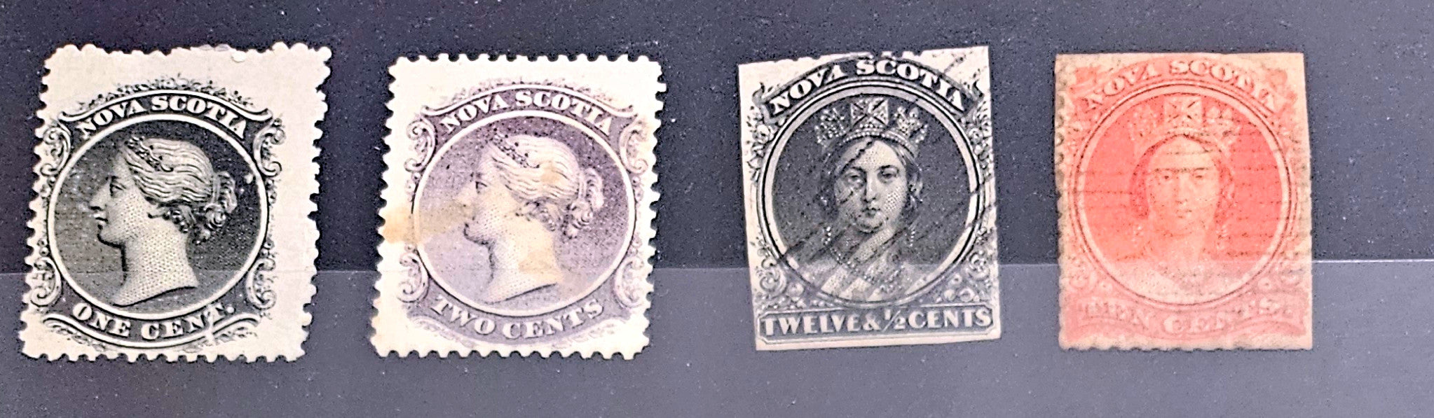 Four vintage Nova Scotia stamps with different designs and colors on a dark background