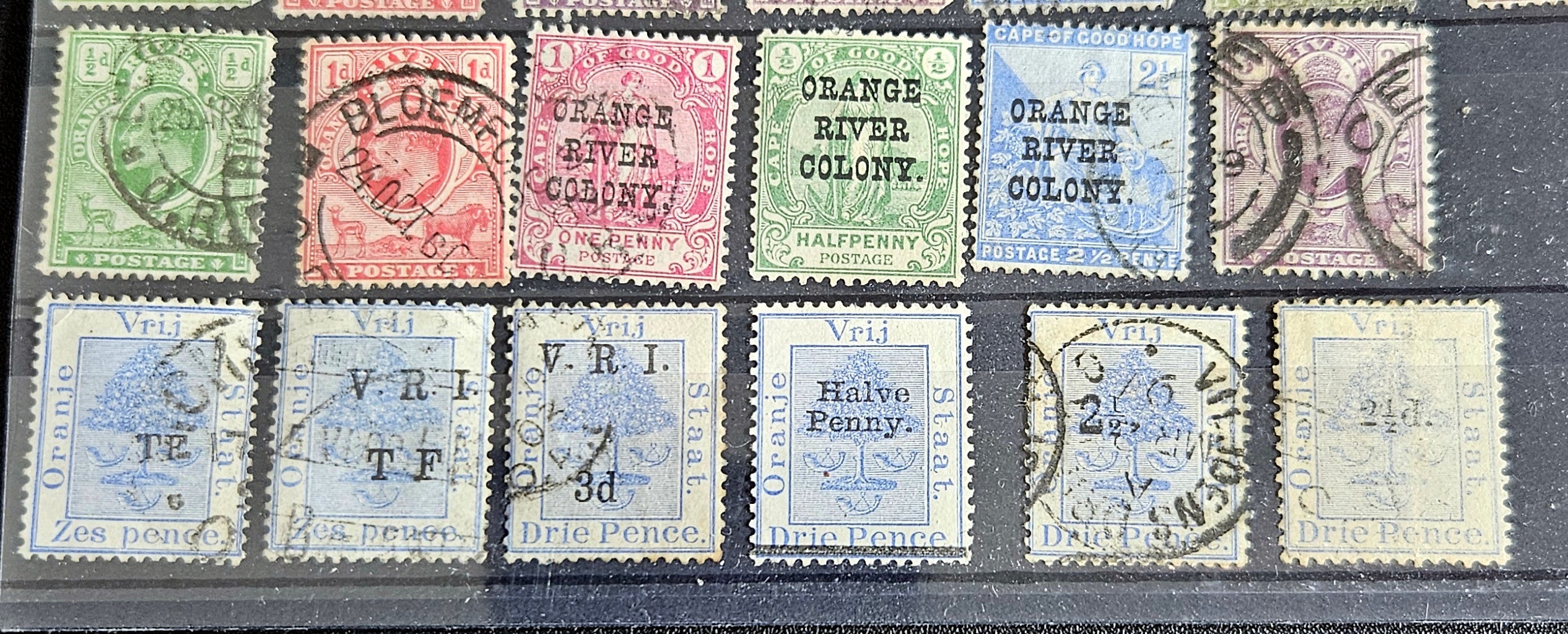 A collection of vintage postage stamps from the Orange Free State, featuring various denominations and cancellation marks, housed in a plastic sleeve.