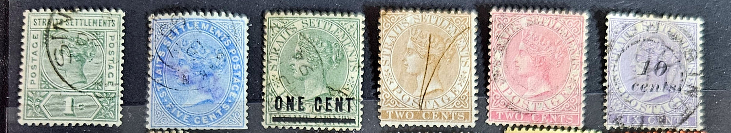 A collection of vintage postage stamps from the Straits Settlements, featuring various colors and designs, displayed on a flat surface.