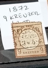 A vintage German stamp from 1872 with a 9 Kreuzer denomination, showing signs of wear and aging.