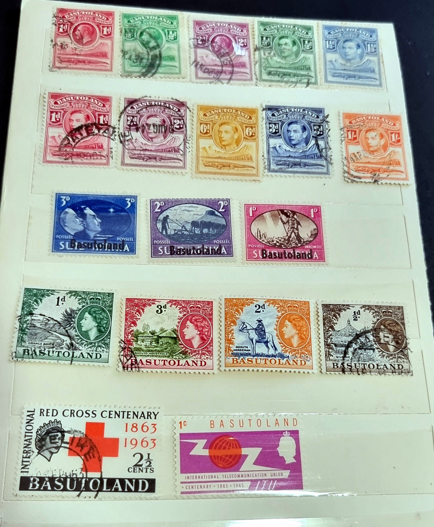 A collection of various Basutoland vintage stamps displayed on a page, with different colors and designs, including a depiction of King George V and Queen Elizabeth II.