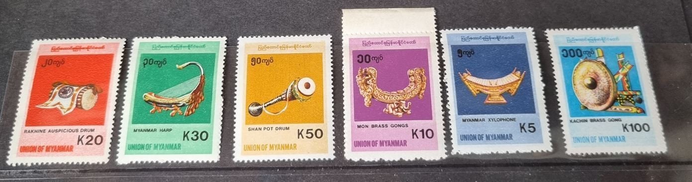 A set of six colorful postage stamps featuring various musical instruments, with a focus on traditional Burmese instruments.