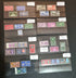 A collection of various commemorative postage stamps featuring Queen Elizabeth II, arranged in a clear plastic case with descriptive labels.