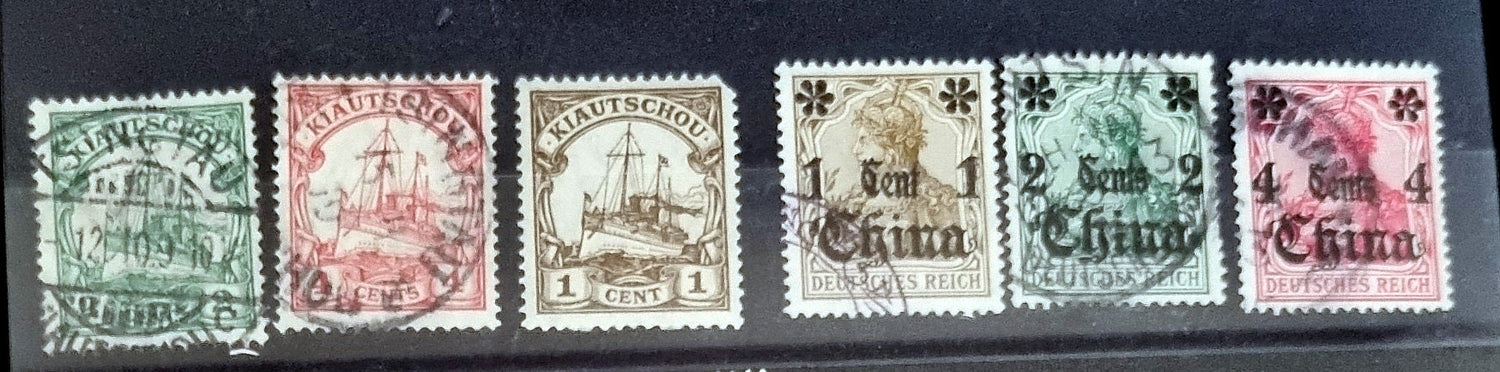 A collection of vintage postage stamps from various German colonies, featuring different colors and designs, arranged in a row on a white background.