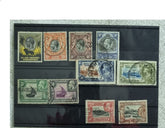A display of various postage stamps from Kenya, Uganda, and Tanganyika featuring portraits of King George V, King George VI, and Queen Elizabeth II.