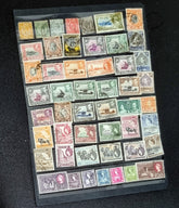 A display of various postage stamps from Kenya, Uganda, and Tanganyika featuring portraits of King George V, King George VI, and Queen Elizabeth II.
