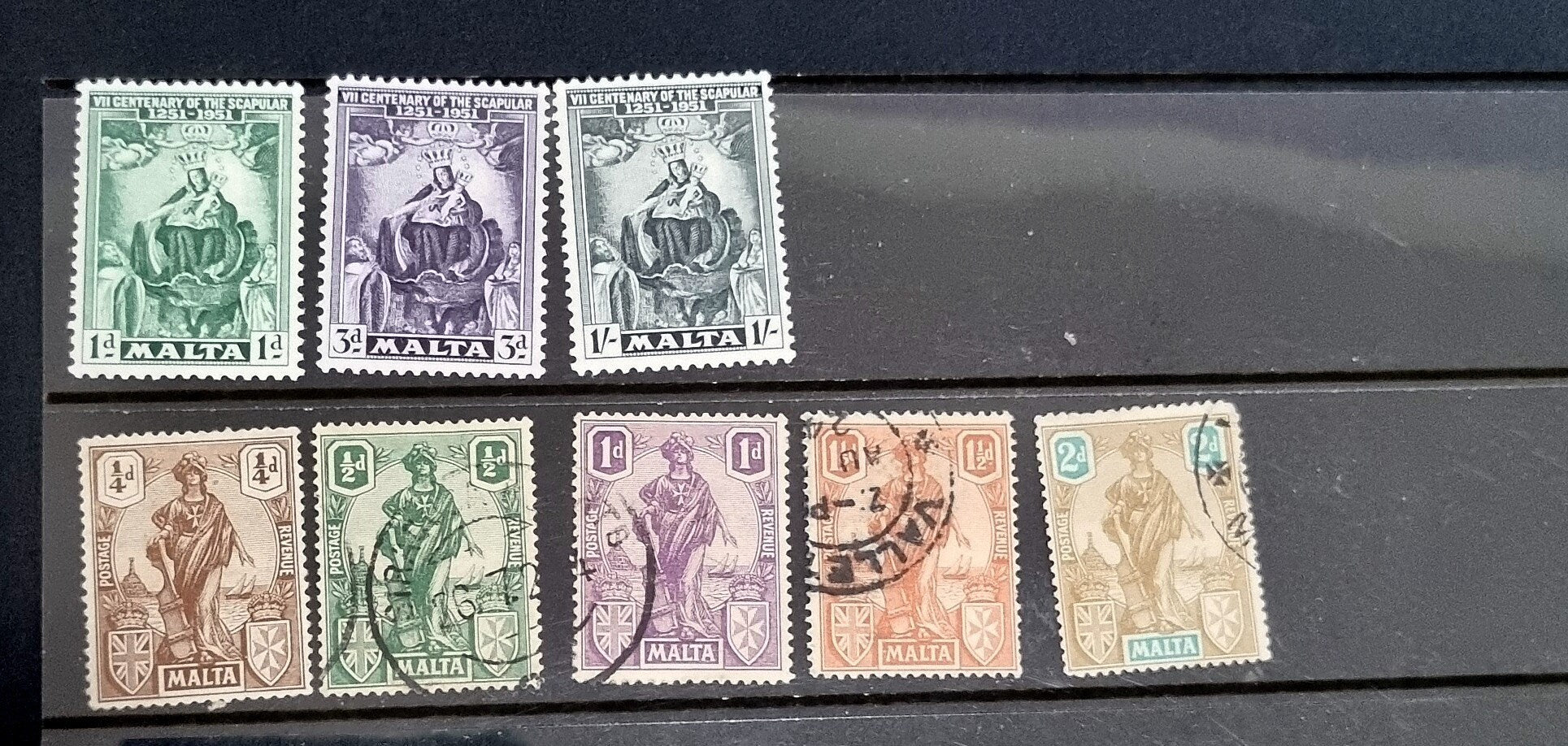 A collection of vintage postage stamps from Malta featuring various designs and colors, arranged in no specific order on a surface.