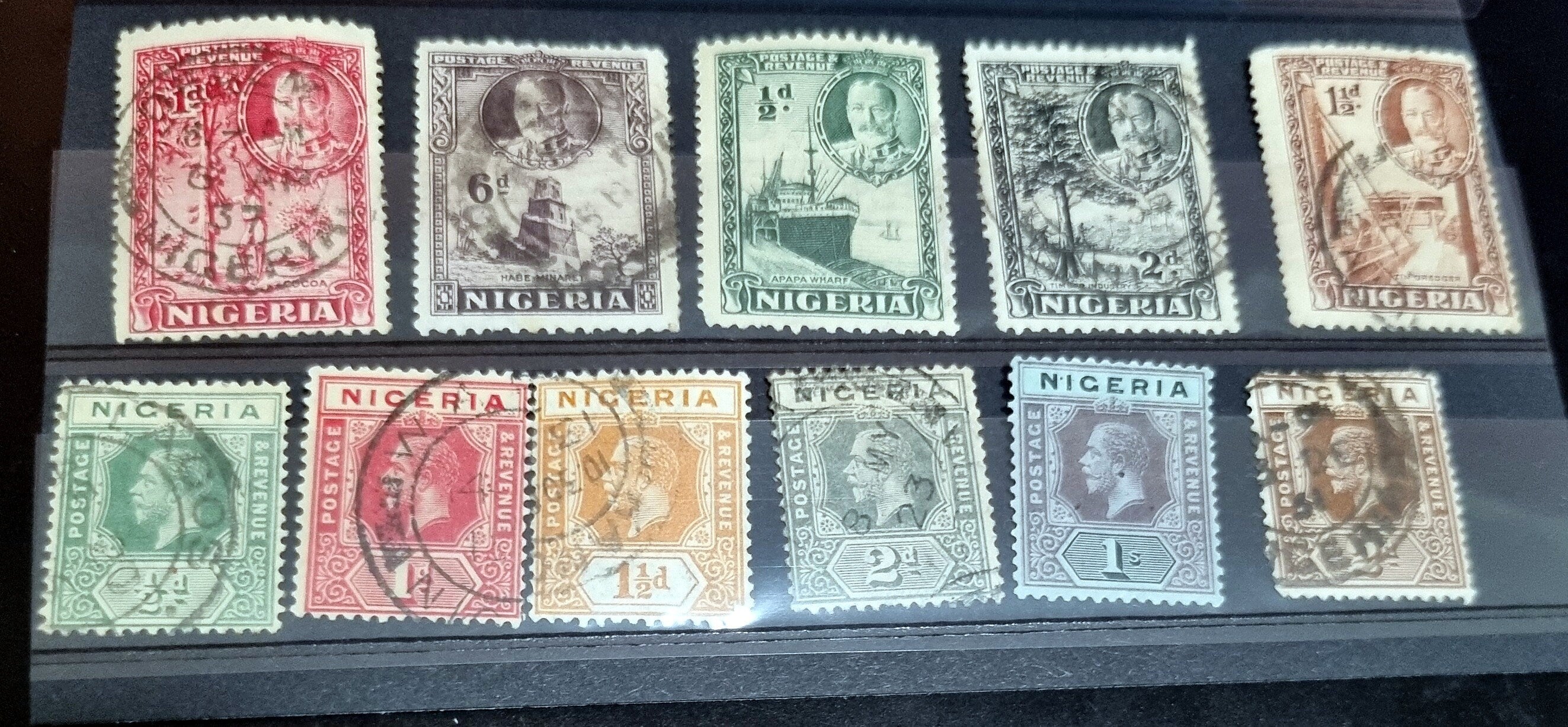 A collection of vintage British Nigeria stamps displayed on a surface, featuring various colors and motifs related to different eras in Nigerian history.