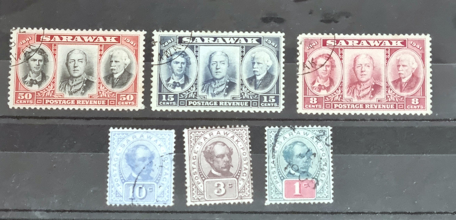 A collection of vintage Sarawak postage stamps displayed on a surface, showcasing various designs and colors including blue, red, and gray tones.