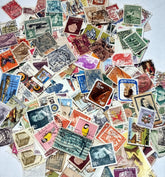 A collection of various postage stamps arranged in a pile, featuring different colors and designs, with no duplicates.