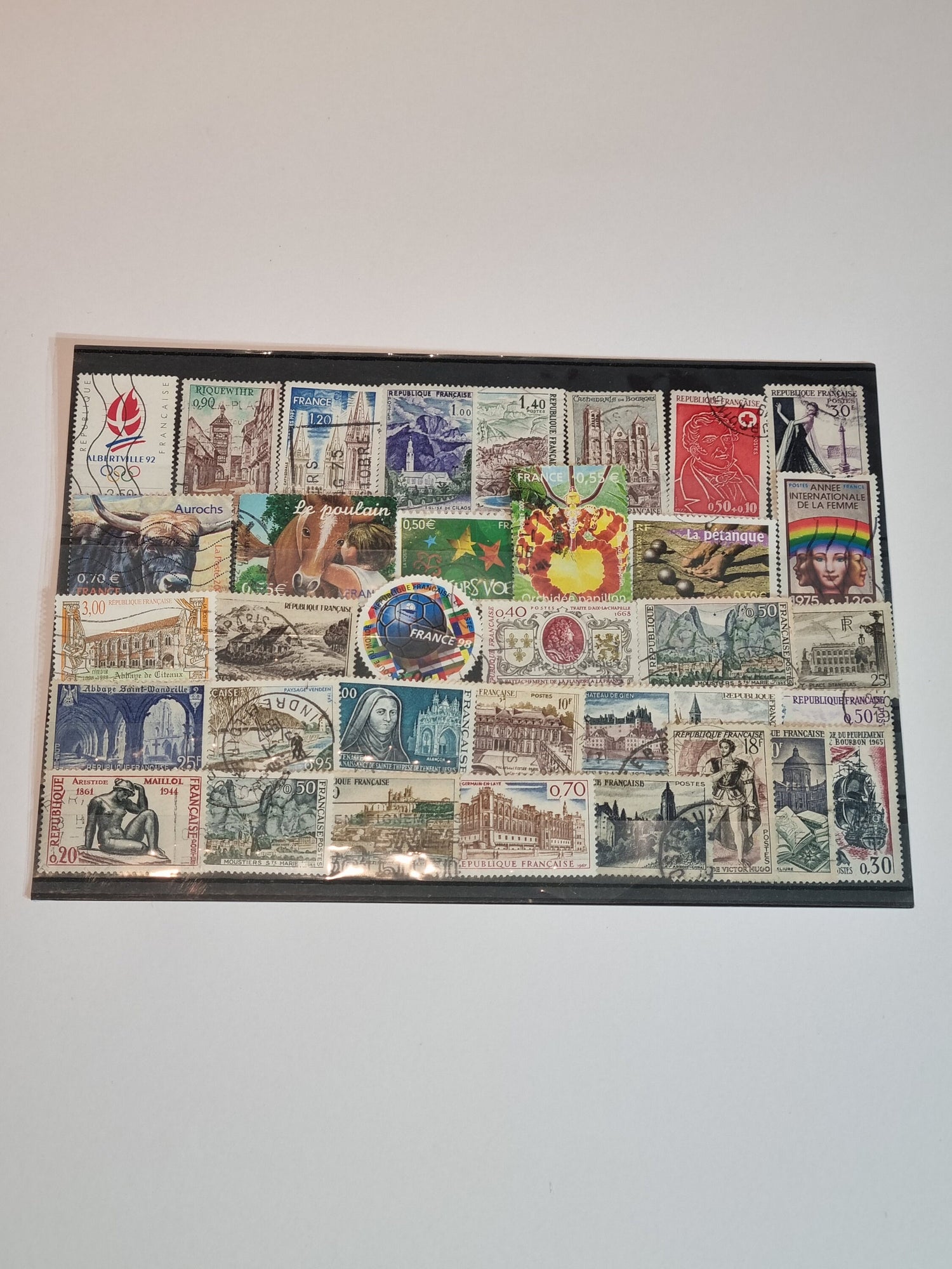 A collection of various postage stamps arranged in a pile, featuring different colors and designs, with no duplicates.