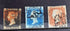 Three vintage British postage stamps displayed side by side on a dark background: a brown one penny stamp with Queen Victoria&