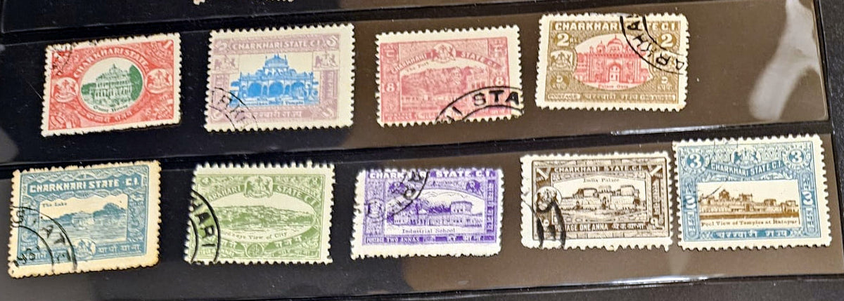A collection of vintage postage stamps displayed on a black surface. The stamps feature various colors including red, blue, green, purple, and brown, with some showing postmarks and others displaying architectural illustrations.