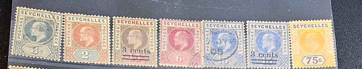 A row of vintage Seychelles postage stamps displayed side by side on a dark background, showing denominations from 3 cents to 75 cents with colors including green, orange, brown, red, blue, and yellow.
