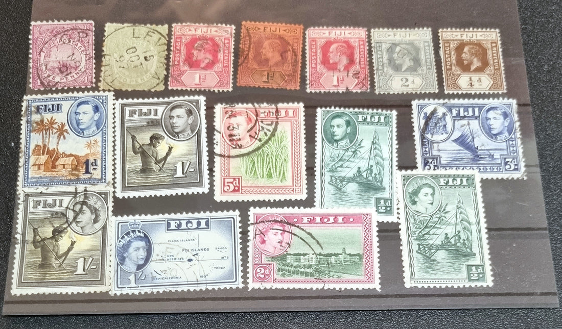 A collection of vintage Fiji British Commonwealth stamps from various reigns, displayed on a surface.