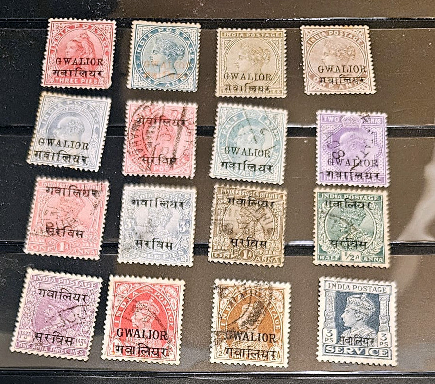 A set of 15 vintage British Indian postage stamps from Gwalior, arranged in a 3x5 grid on a dark display card. The stamps feature various colors including red, blue, purple, green, and brown, with some showing Queen Victoria&