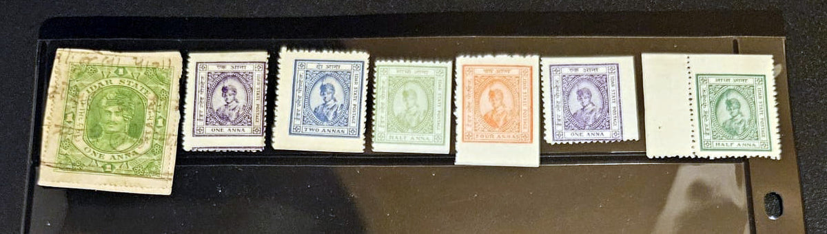 A set of six vintage postage stamps displayed side-by-side on a black surface. The stamps feature various colors including green, purple, blue, and orange, with one being a worn green stamp on the left.