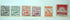 Six vintage Japanese postage stamps in different colors (blue-gray, green, orange, purple, red-orange, and red) lined up horizontally on a white background.