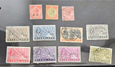 A set of vintage Nyasaland postage stamps arranged on a dark surface. The collection includes stamps in red, orange, pink, blue, gray, brown, purple, and olive-green colors, with some showing postmark cancellations and others featuring the word &