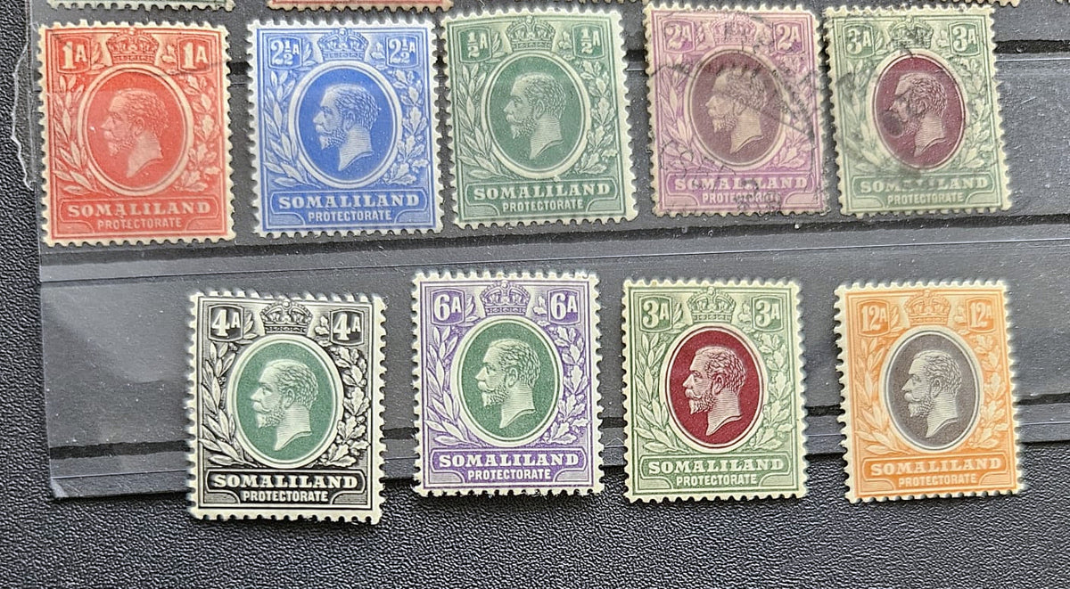 A set of ten vintage Somaliland postage stamps from the British Empire, featuring various colors including red, blue, green, purple, orange, and brown, arranged on a black textured surface.