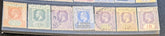 A close-up of a row of vintage Seychelles postage stamps in a clear plastic holder, showing multiple colors including orange, green, blue, purple, and yellow with profile portraits and denominations from 2 to 1R.