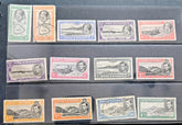 A set of vintage Ascension Island postage stamps arranged in three rows on a dark background. The stamps feature various colors including green, orange, blue, purple, and red, with some showing portrait illustrations and others depicting landscapes.