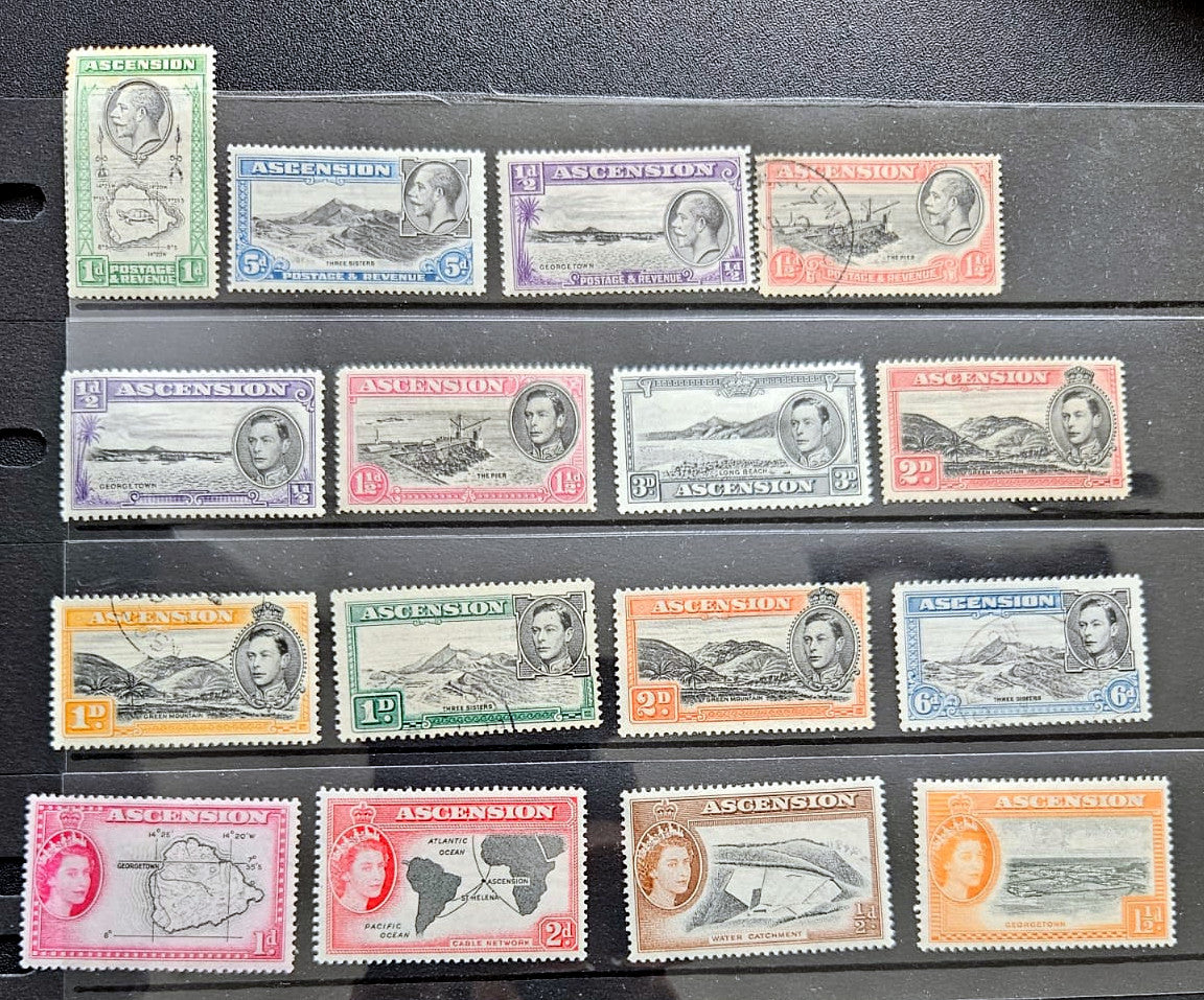 A set of vintage British Ascension Island postage stamps arranged in rows on a black display card. The stamps feature various colors and denominations, including green, blue, purple, orange, and pink, with Queen Elizabeth II&
