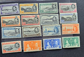 A set of 15 vintage Ascension Island postage stamps from the British Empire, arranged in a 3x5 grid on a black background. The stamps feature various colors including purple, orange, green, blue, and gray, with portraits of King George V and Queen Elizabeth and depictions of ships and landscapes.